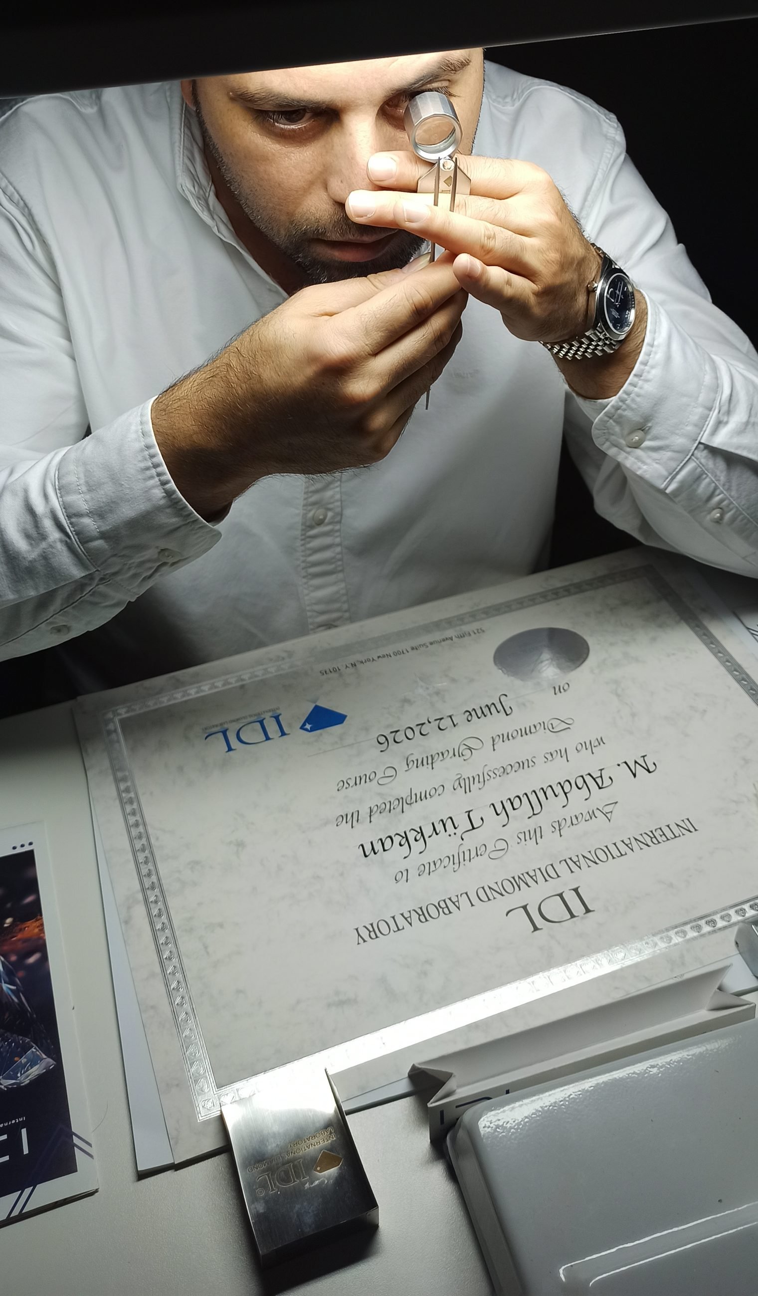 M. Abdullah Türkkan lup ile elmas inceliyor, IDL sertifikası önünde